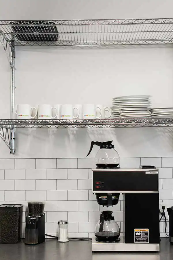 The coffee machine and a shelf of mugs in the Name.com office