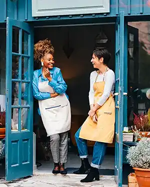 Two female business owners smiling at their store front.