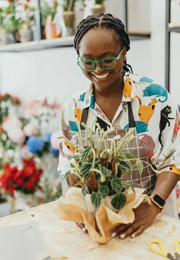 Female florist shop owner assembling a seasonal flower bouquet
