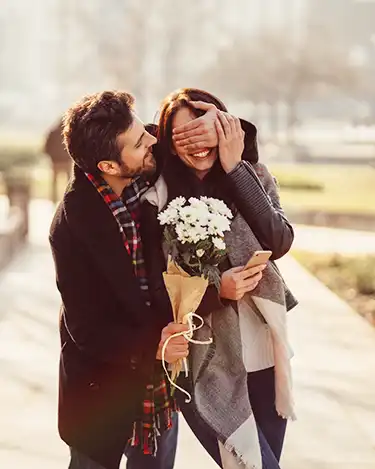 Man surprises his female partner with flowers in the park