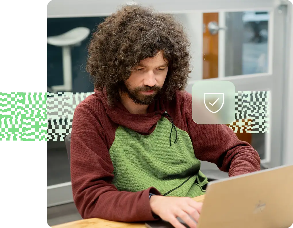 A man smiles while looking at a computer screen