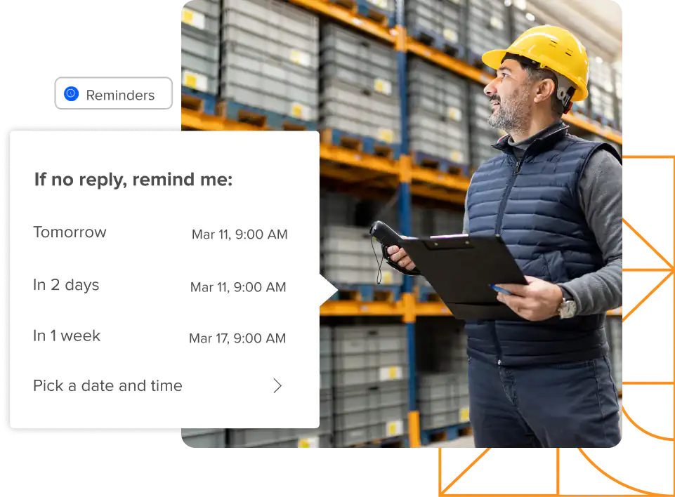 Man wearing hardhat standing in warehouse holding clipboard with screenshot of reminder to reply to email