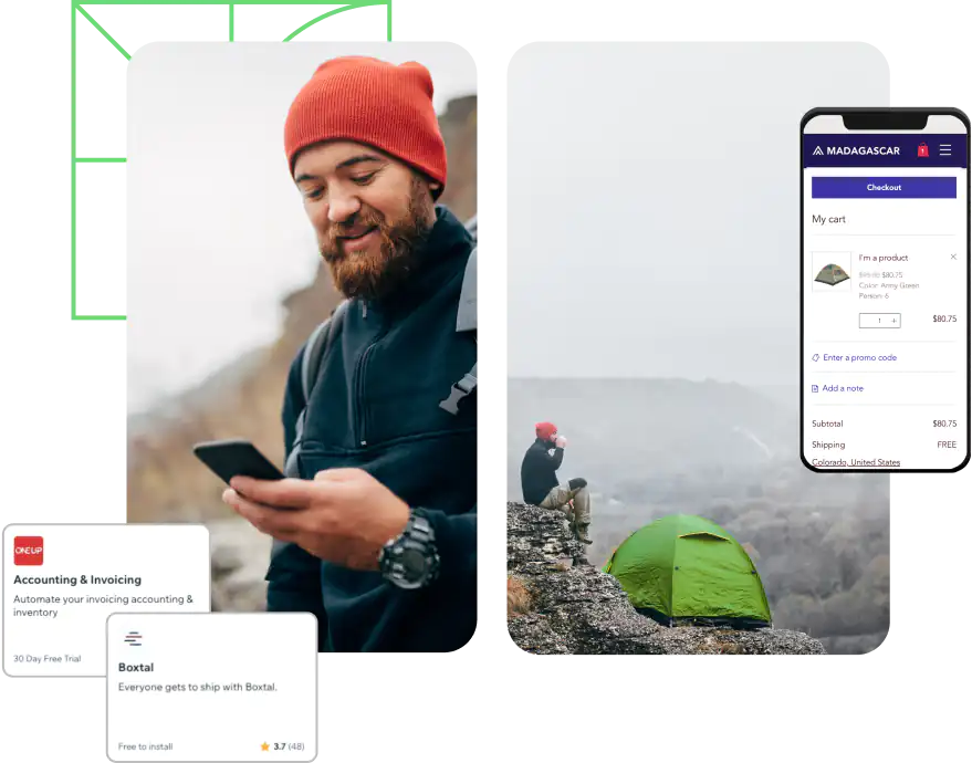 Man camping outdoors stands next to his tent and smiles at his phone