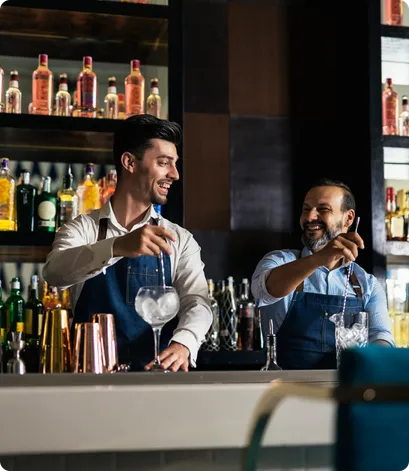 Two male bartender mixing drinks behind a bar