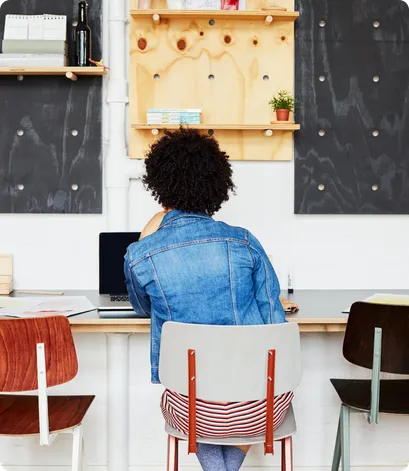 Woman seen with her back turned, working on her laptop