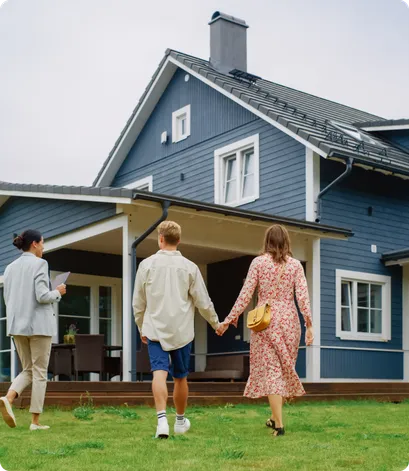 Couple holding hands, walking towards house with real estate agent