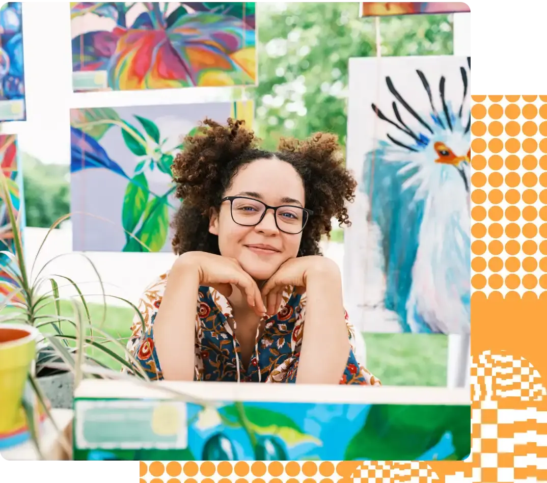 Woman with curly hair and glasses smiling with confidence in her studio